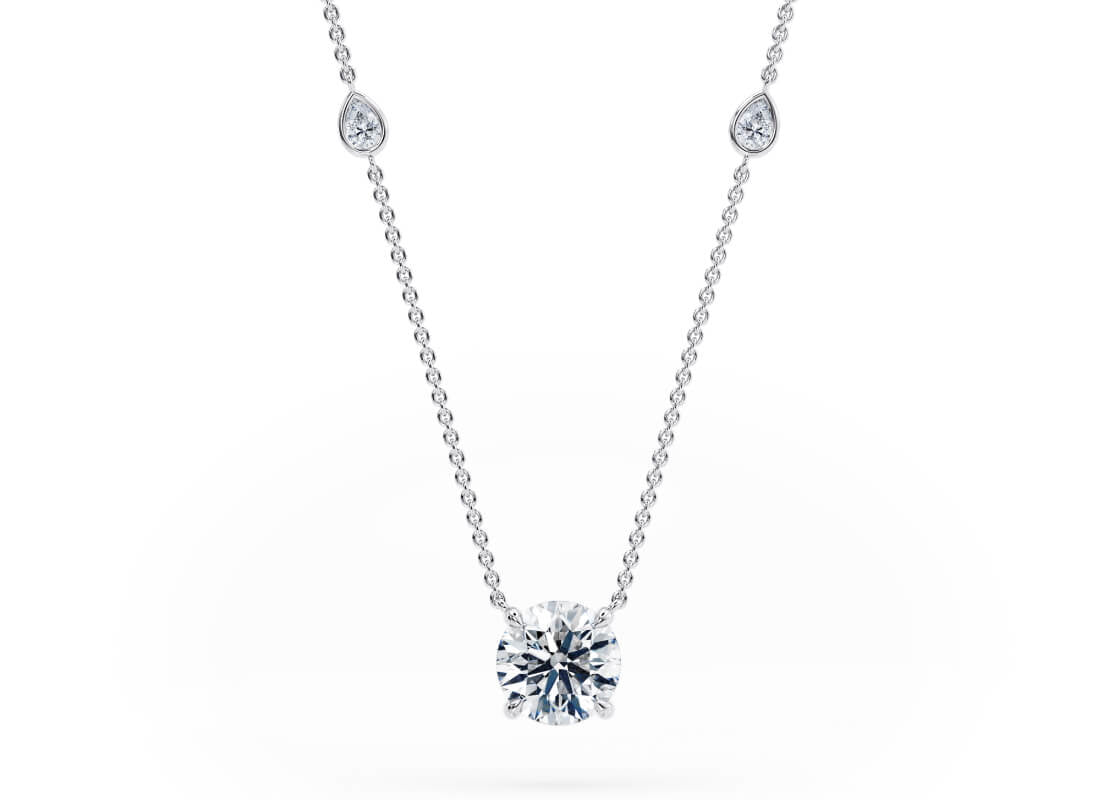 Inspired by the gentle shimmer of morning dew, the Elysia Necklace features pear-cut diamonds along the chain, resembling glistening water droplets. These delicate accents lead the eye to a radiant solitaire stone that seems to float effortlessly- light, graceful, and full of brilliance.